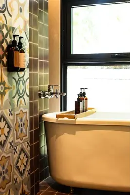 a bathroom with a tub and a sink and a window at Tints of Blue Hotel in Bangkok