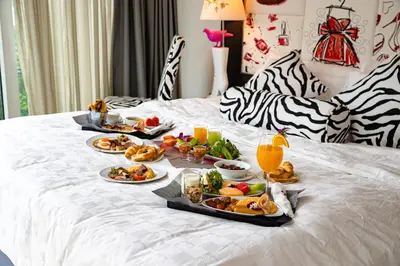 a table with plates of food on a bed at Hotel Clover Asoke - SHA Extra Plus in Bangkok