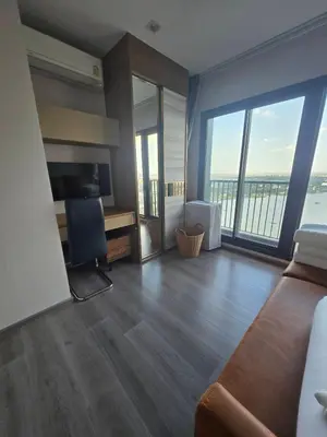 a living room with a couch and a desk and windows at The Politan Aqua in Ban Sai Ma