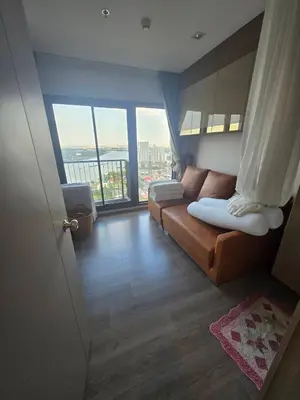 a living room with a couch and a large window at The Politan Aqua in Ban Sai Ma
