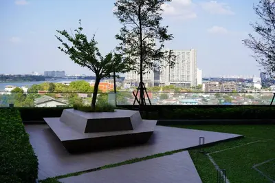 a bench in a park with a view of a city at The Politan Aqua in Ban Sai Ma