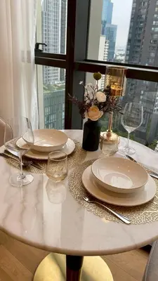a table with plates and wine glasses and a window at ห้องพักใจกลางกรุงเทพฯ ใกล้สยาม in Pratunam