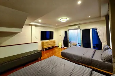 a bedroom with two beds and a flat screen tv at The Atlas hostel Bangkok in Thung Si Kan