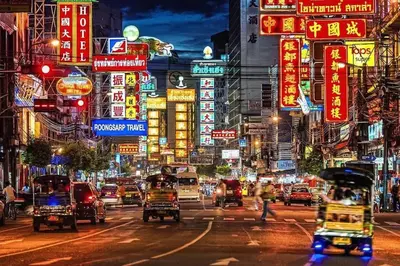 a busy city street at night with cars and signs at Merge Hostel in Samphanthawong
