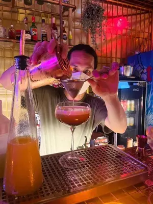 a man pouring a drink into a martini glass at Merge Hostel in Samphanthawong