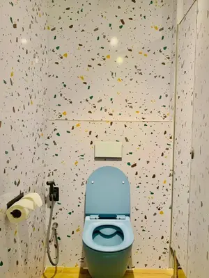 a bathroom with a toilet with confetti on the wall at Easy Monday Capsule Bed and Traditional Thai Bath in Bangkok