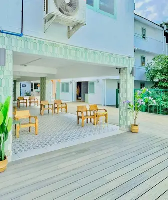 a patio with wooden tables and chairs and a building at Easy Monday Capsule Bed and Traditional Thai Bath in Bangkok