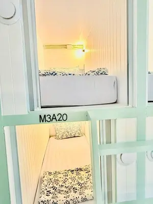 a small room with a bed and a mirror at Easy Monday Capsule Bed and Traditional Thai Bath in Bangkok
