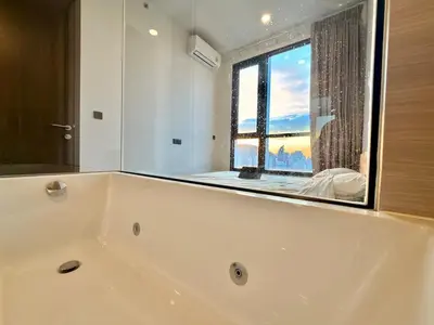 a bathroom with a bath tub with a large window at Private Skyrise view on thonglor in Bangkok