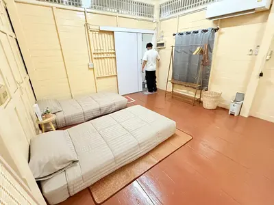 a man standing in a room with a couch at Muzachi home stay and canal in Bangkok Yai