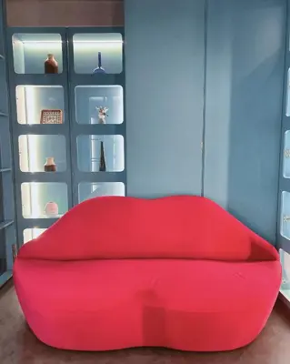 a red couch in a room with some shelves at Lesbase Women Hostel in Bangkok