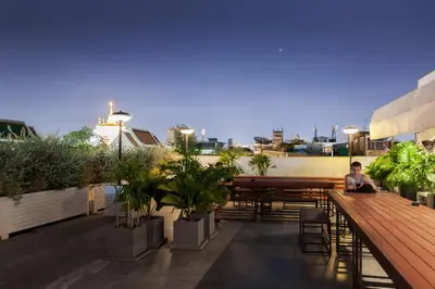 a man sitting on top of a balcony with plants at Once Again Hostel in Bangkok