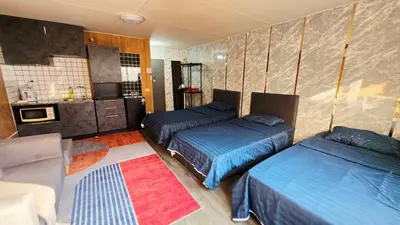a bedroom with two beds and a kitchen with a couch at อิมแพ็ค เมืองทองธานี ห้องเช่ารายวัน เมืองทอง คอนโดเมืองทอง c9