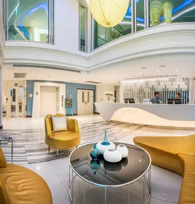 a lobby with yellow chairs and a coffee table at Le Tada Parkview Hotel in Bangkok