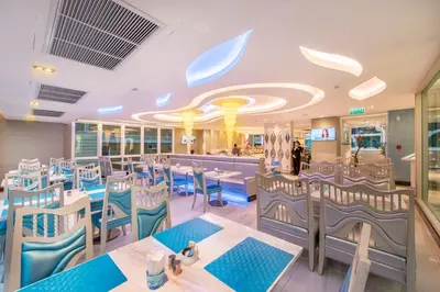 a dining room with tables and blue chairs at Le Tada Parkview Hotel in Bangkok