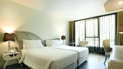 a hotel room with a bed and a large window at Le Tada Parkview Hotel in Bangkok