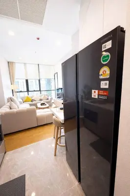 a black refrigerator in a living room with a couch at Luxury 1 Bedroom l BTS 2 mins l Pool and Gym in Pratunam