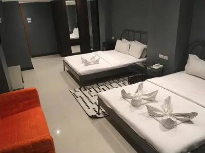 a hotel room with two beds and a chair at Cloud 9 Lodge in Bangkok