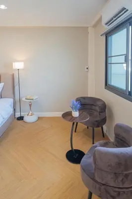 a room with a bed and two chairs and a table at Warm & Cozy Family Home, Near BTS Punnawithi in Phra Khanong