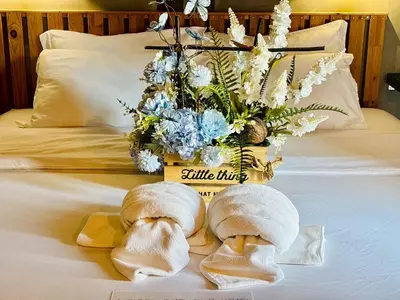 two towels on a bed with a vase of flowers at Bangkok Phattanakan32 guest house in Bangkok