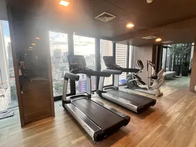 a gym with three tread machines in a room with windows at City life Nana - near Bumrungrad Hospital in Bangkok