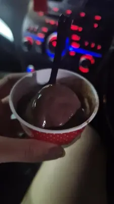 a hand holding a bowl of chocolate pudding with a spoon at Lionkey in Taling Chan
