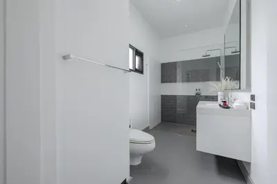 a white bathroom with a toilet and a sink at Thong Lo Sumptuous Double Pool Villa in Bangkok
