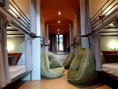 a room with two bunk beds and two chairs at Nitra Hostel Siriraj in Bangkok