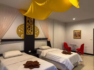 two beds in a room with red chairs at POR SAHA Hotel Ramkhamhaeng 100 in Bang Kapi