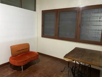 a room with a chair and a wooden table at PAMA'Pranakorn in Bangkok