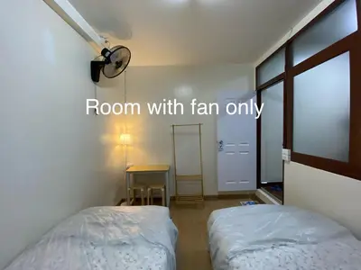 a room with two beds and a table with a window at PAMA'Pranakorn in Bangkok