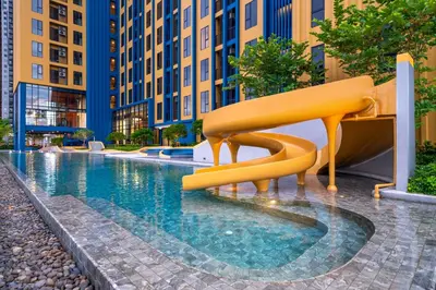 a yellow slide in the middle of a swimming pool at Plum New West - Pool View in Ban Bang Krabu