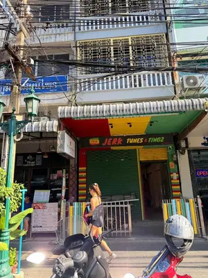 a woman riding a motorcycle in front of a store at The Green Bean Hostel Khaosan in Bangkok
