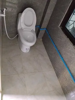 a bathroom with a toilet with a blue hose at The Green Bean Hostel Khaosan in Bangkok