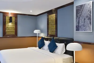 a bedroom with two beds with blue walls and two lamps at THE BRETON Hotel in Ban O Pao