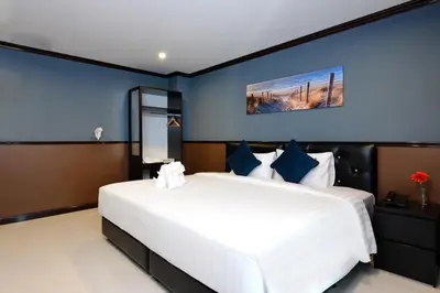 a bedroom with a large white bed with blue walls at THE BRETON Hotel in Ban O Pao