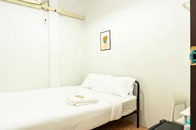 a small bedroom with a bed with white sheets at BAO The Giant Swing - เบา ศาลเจ้าพ่อเสือ ถนนตะนาว in Bangkok