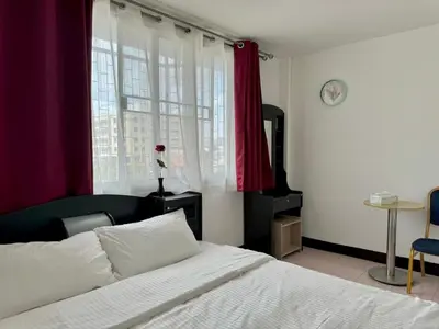 a bedroom with a white bed and a window at Baan Kalaya Homestay in Nonthaburi