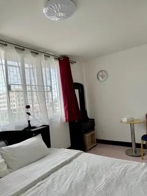 a bedroom with a white bed and a red curtain at Baan Kalaya Homestay in Nonthaburi