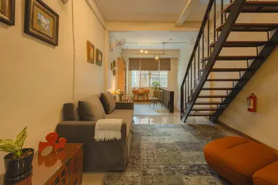 a living room with a couch and a staircase at Oasis Thai Teak Home in Sathorn in Yan Nawa