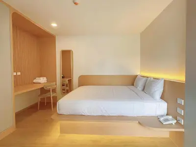 a bedroom with a white bed and a desk at Wynora Hotel in Khlong Toei