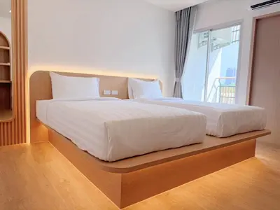 a bedroom with a large white bed with a window at Wynora Hotel in Khlong Toei