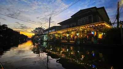 a building with lights on a canal at sunset at นำสมัย สุขใจ สนามชัย in Bangkok