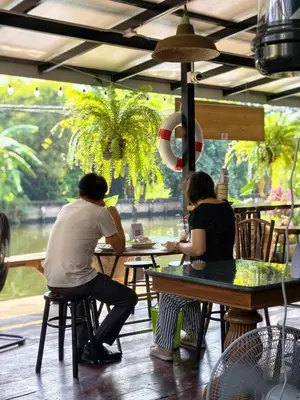 a couple of people sitting at tables in a restaurant at นำสมัย สุขใจ สนามชัย in Bangkok