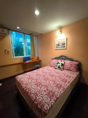 a bedroom with a bed with a red bedspread and a window at Santo house no66 in Bangkok