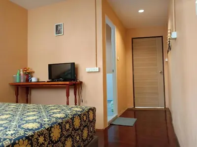 a bedroom with a bed and a television and a door at Santo house no66 in Bangkok