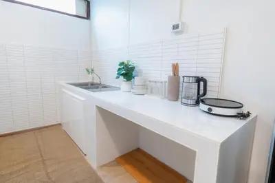 a white kitchen with a counter with a sink at Stay Ekkamai - Private Pool villa, Central Bangkok in Bangkok