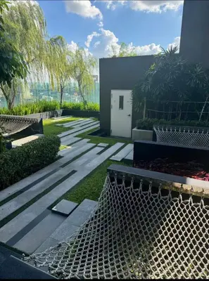 a garden with a bench and a building at BTS Skytrain Thonglor station sukhumwit 36-38 in Bangkok