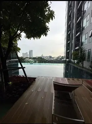 a wooden bench sitting next to a large body of water at BTS Skytrain Thonglor station sukhumwit 36-38 in Bangkok