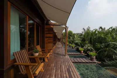 a row of wooden benches on a porch of a building at Baan Krai Nao The Riverfront in Bang Chak